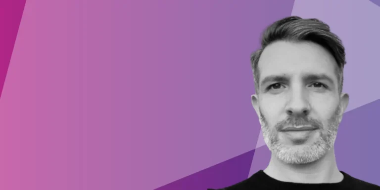 A greyscale portrait of a man with short hair and a beard on the right side, set against a geometric pink and purple background.