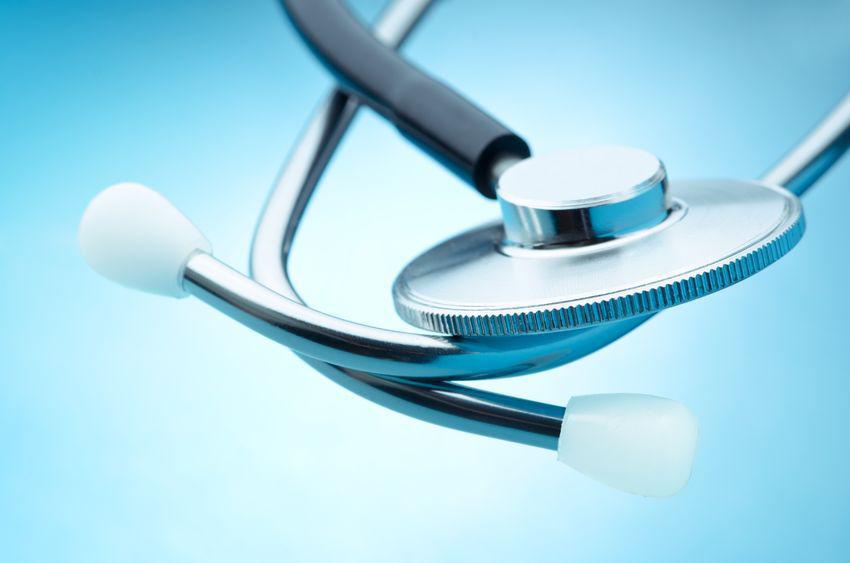 A close-up of a stethoscope with a metallic chestpiece and white eartips, set against a light blue background.