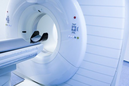A close-up view of a modern MRI machine in a medical facility, with the patient table partially extended, ready for a scan.