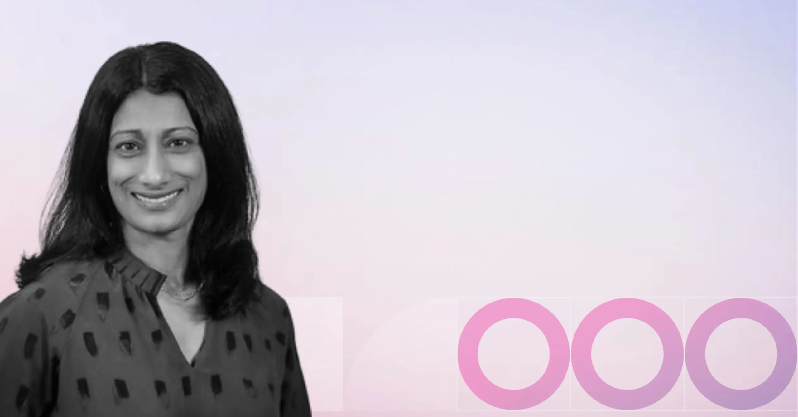 A woman with shoulder-length dark hair wearing a patterned blouse smiles at the camera. The background is a soft gradient with three pink circles on the lower right side.