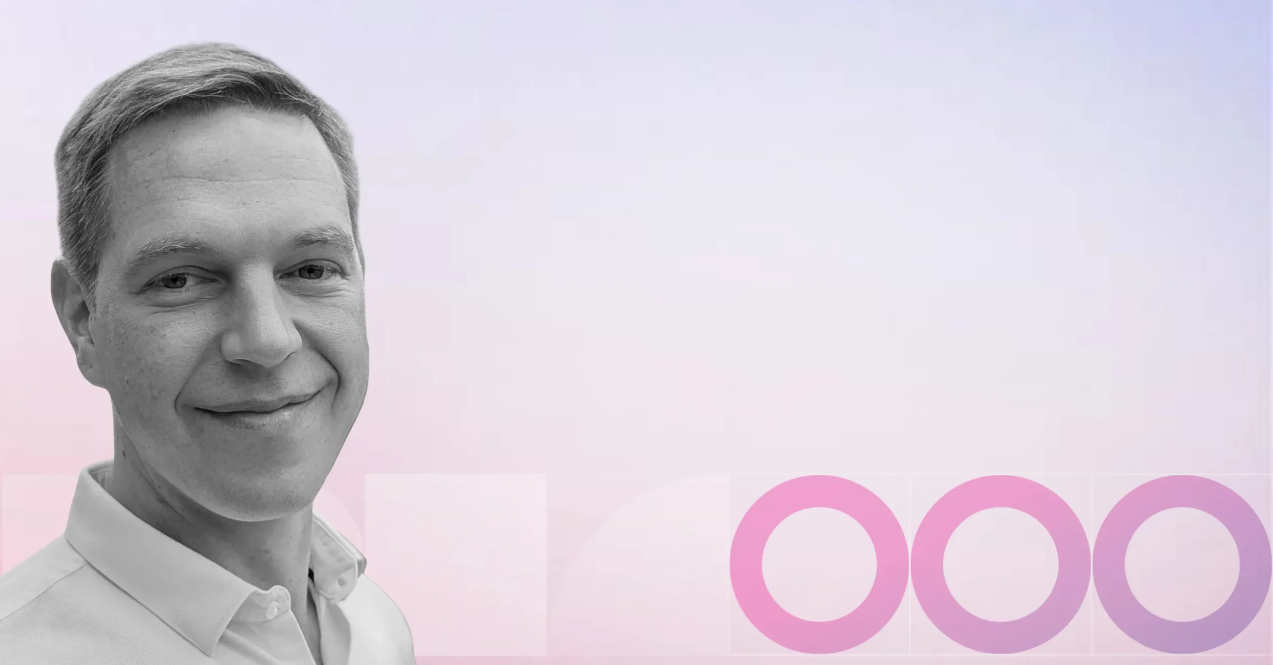 A man smiling in the left foreground, with a soft pastel gradient background and three overlapping pink circles on the right.