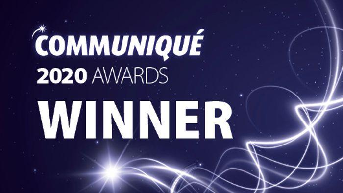 Text reading COMMUNIQUÉ 2020 AWARDS WINNER on a dark blue background with white glowing lines and sparkles.