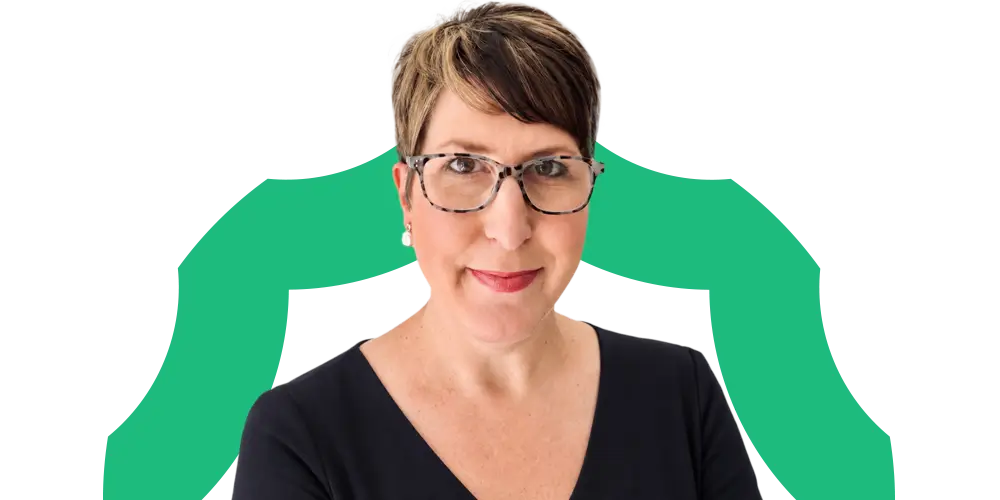 A person with short brown hair, glasses, and a black top stands in front of a white background with a green abstract shape behind them.