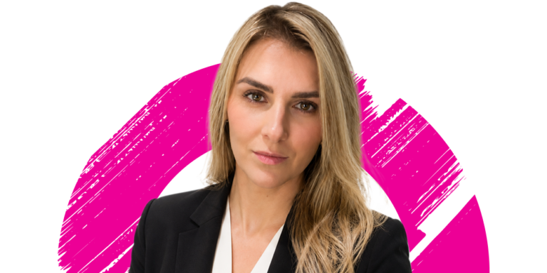 A woman with long blonde hair wearing a black blazer and white blouse stands in front of a white background with a bold, pink brushstroke design.