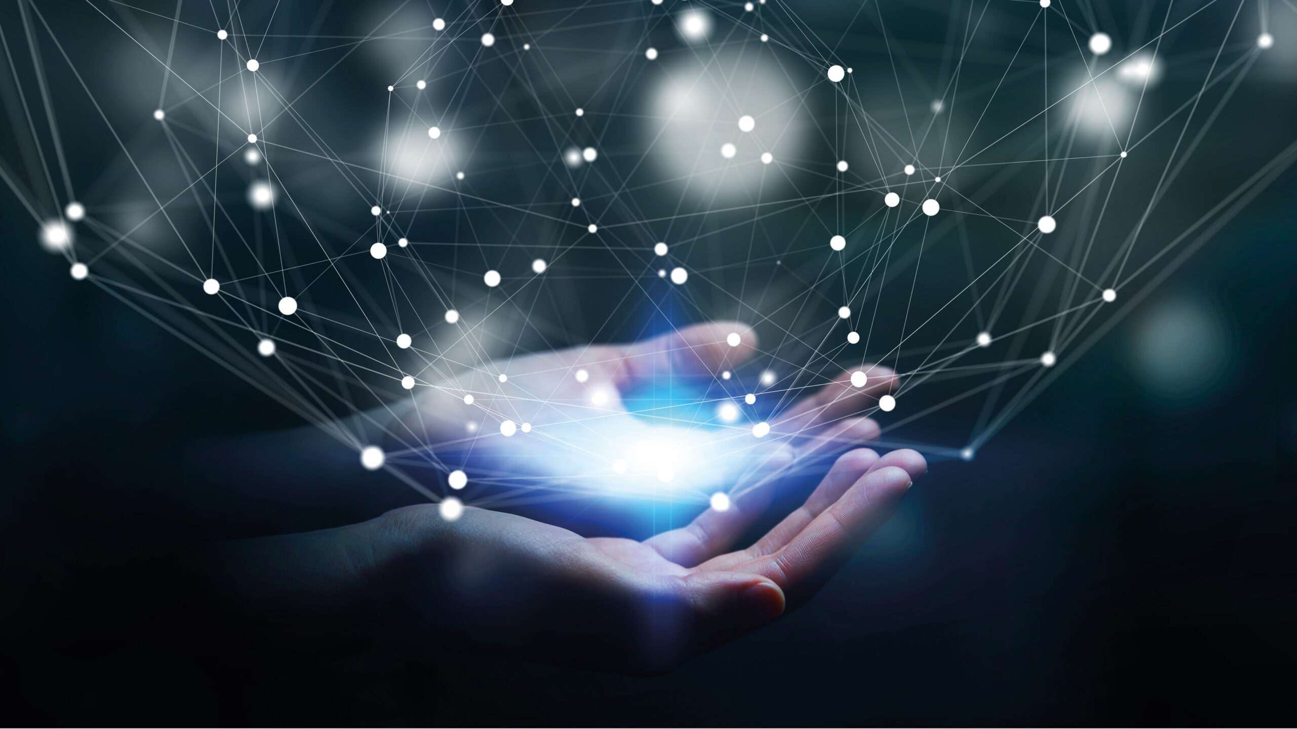 A pair of hands cupping glowing light, with a digital network of interconnected nodes and lines floating above, symbolising technology and connectivity.