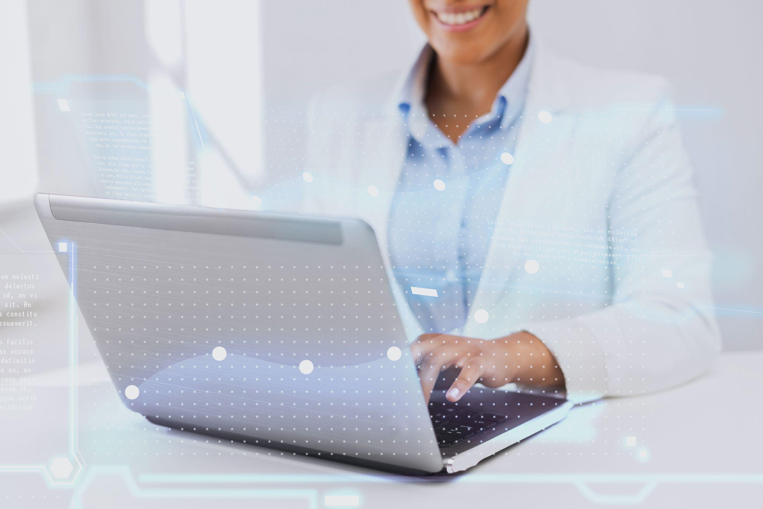 A person in a white blazer smiles whilst typing on a laptop, with futuristic digital graphics overlaid, symbolising technology and innovation.