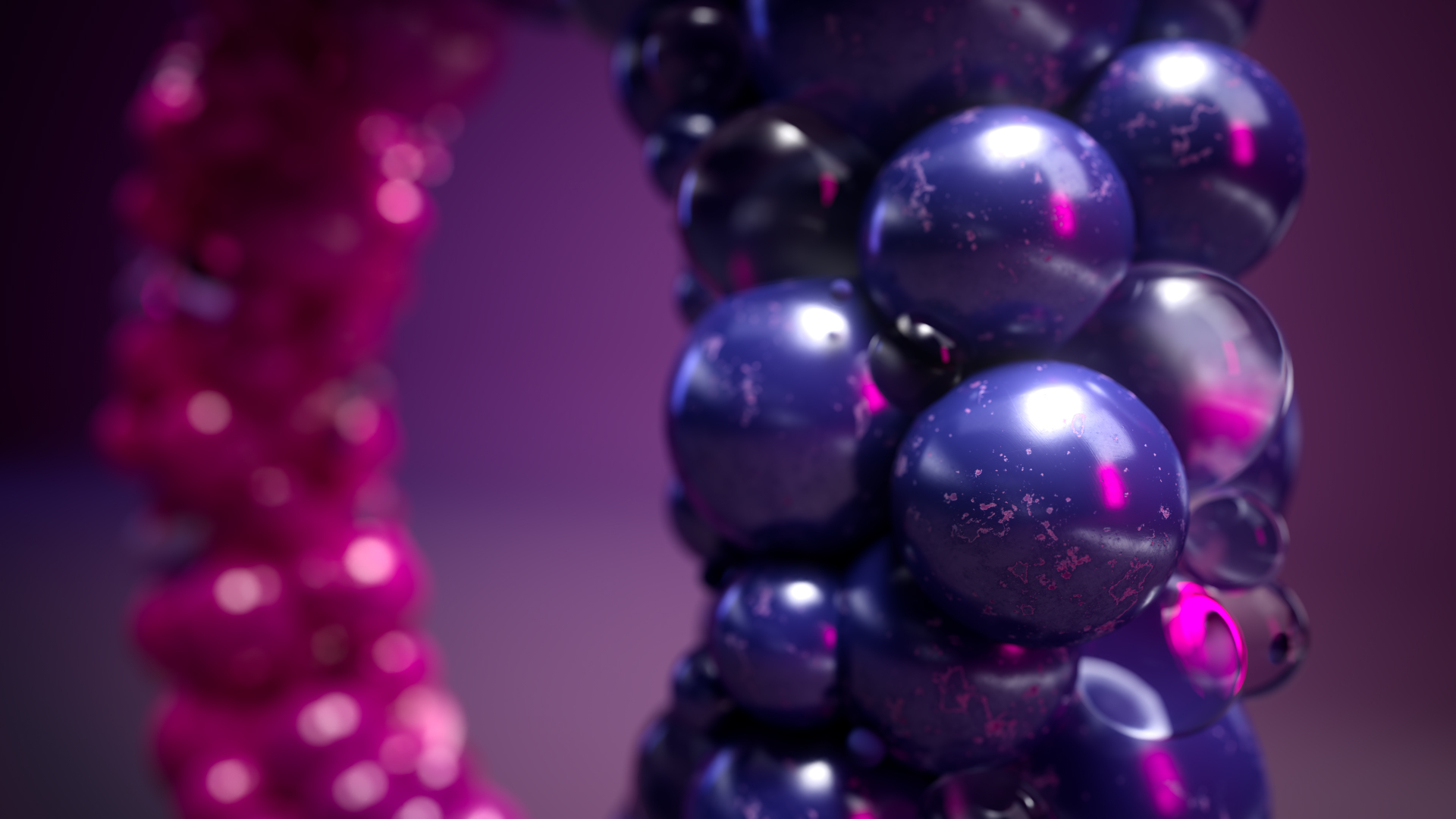 A close-up of glossy, reflective spheres clustered together, mostly in dark blue and purple tones, with pink highlights and a blurred pink cluster in the background.