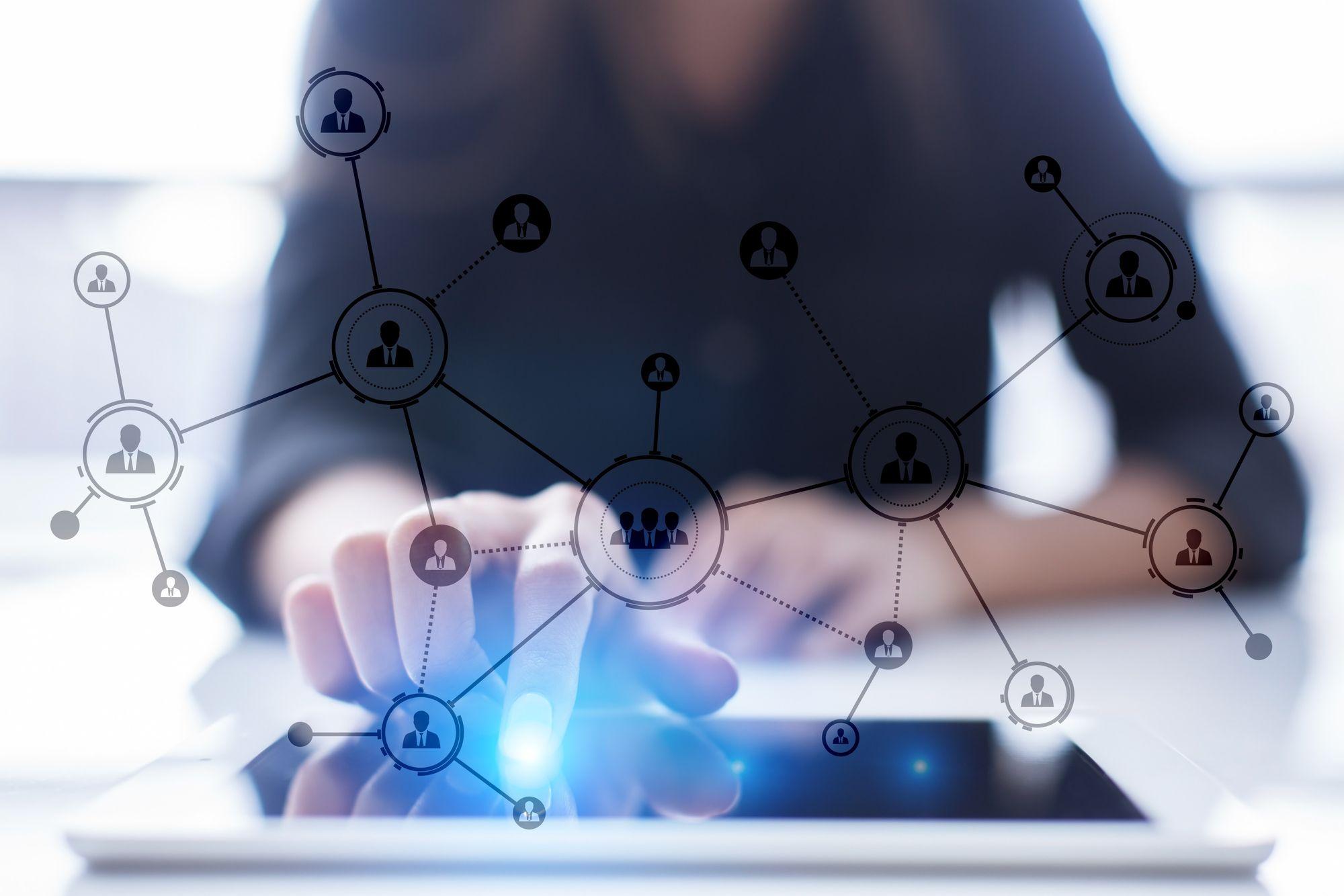 A person touches a tablet screen with network icons and lines overlaid, representing digital connections and social networking concepts.