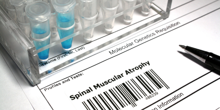 Close-up of a genetics request form labelled Spinal Muscular Atrophy with a barcode, beside a pen and a container holding several laboratory test vials filled with blue liquid.