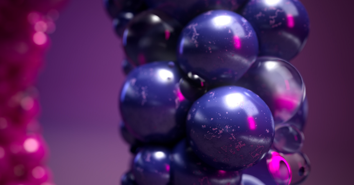 A close-up of glossy, dark purple spheres clustered together, reflecting pink and purple light on a blurred purple background.