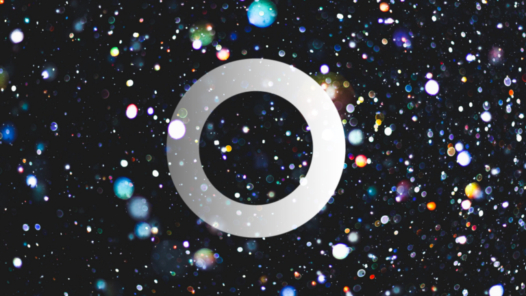 A white ring centred on a black background filled with colourful, blurred light spots resembling stars or bokeh effects.