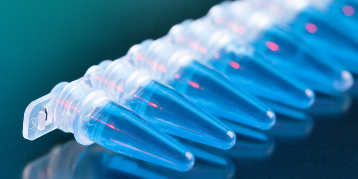 A row of clear plastic microcentrifuge tubes filled with blue liquid, aligned on a reflective surface with a green and blue background.