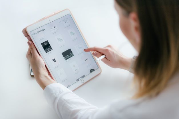 A person uses a stylus to navigate drawings and graphics displayed on a tablet screen.