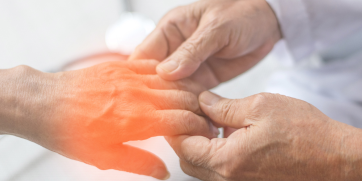A doctor gently examines a patient's inflamed hand, highlighting possible pain or arthritis, with a warm orange glow indicating the affected area.