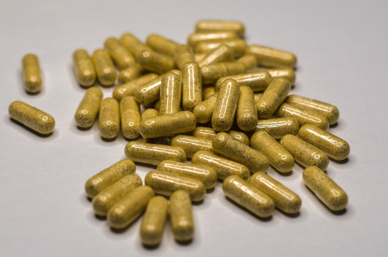 A pile of yellowish capsules scattered on a white surface.