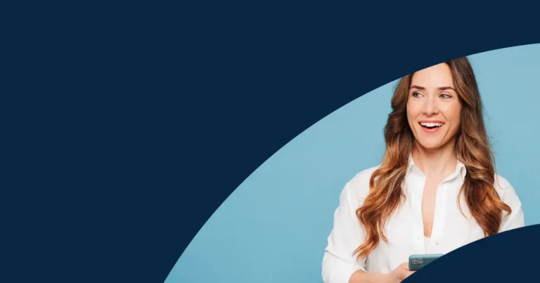 Smiling woman with long brown hair, wearing a white shirt, holding a mobile. She stands against a blue background with a navy curved design partially covering the image.