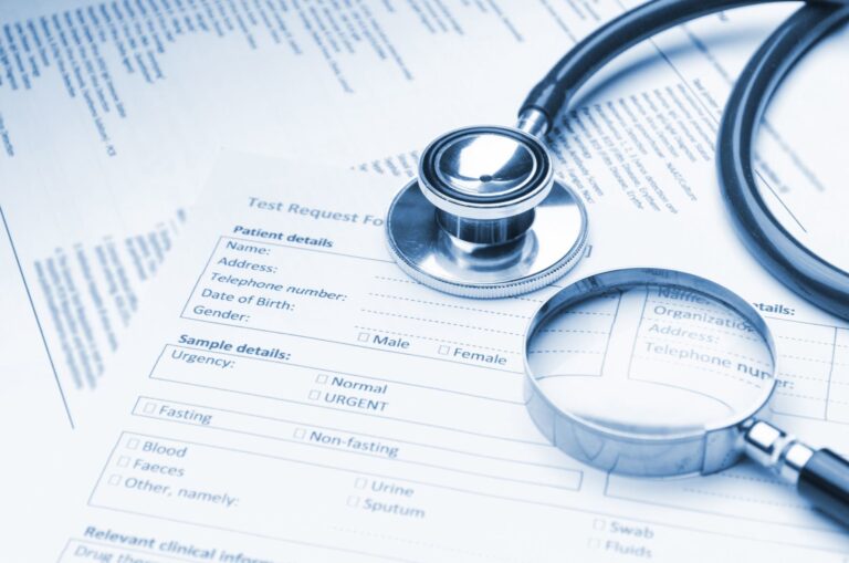 A stethoscope and magnifying glass rest on medical test request forms, highlighting sections for patient details and test options, symbolising healthcare and medical examination processes.