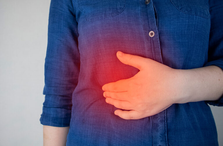 A person in a blue shirt holds their stomach, with a red glow indicating pain or discomfort in the abdominal area.